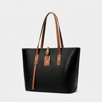 Black leather tote bag with brown handles and gold hardware on white background