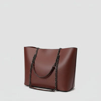 Brown leather tote bag with black chain shoulder straps on a plain white background