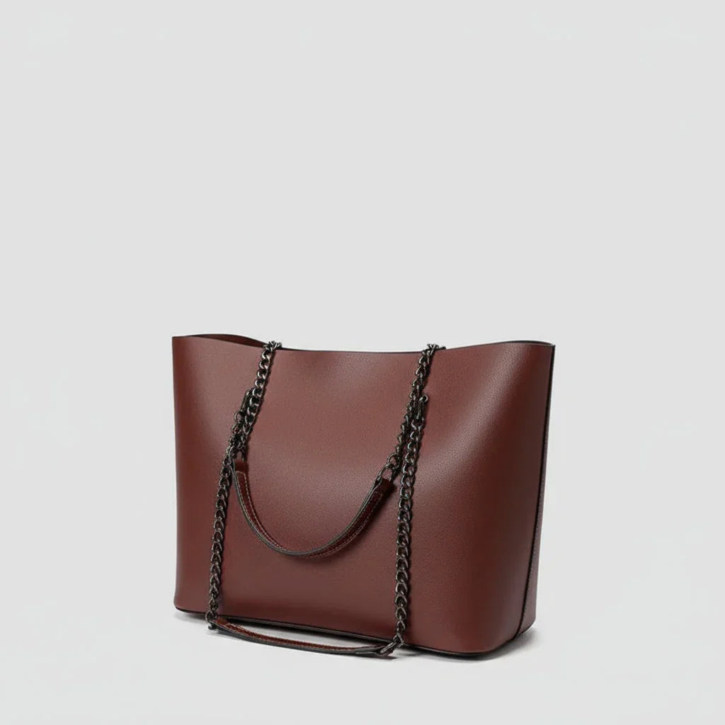 Brown leather tote bag with black chain shoulder straps on a plain white background