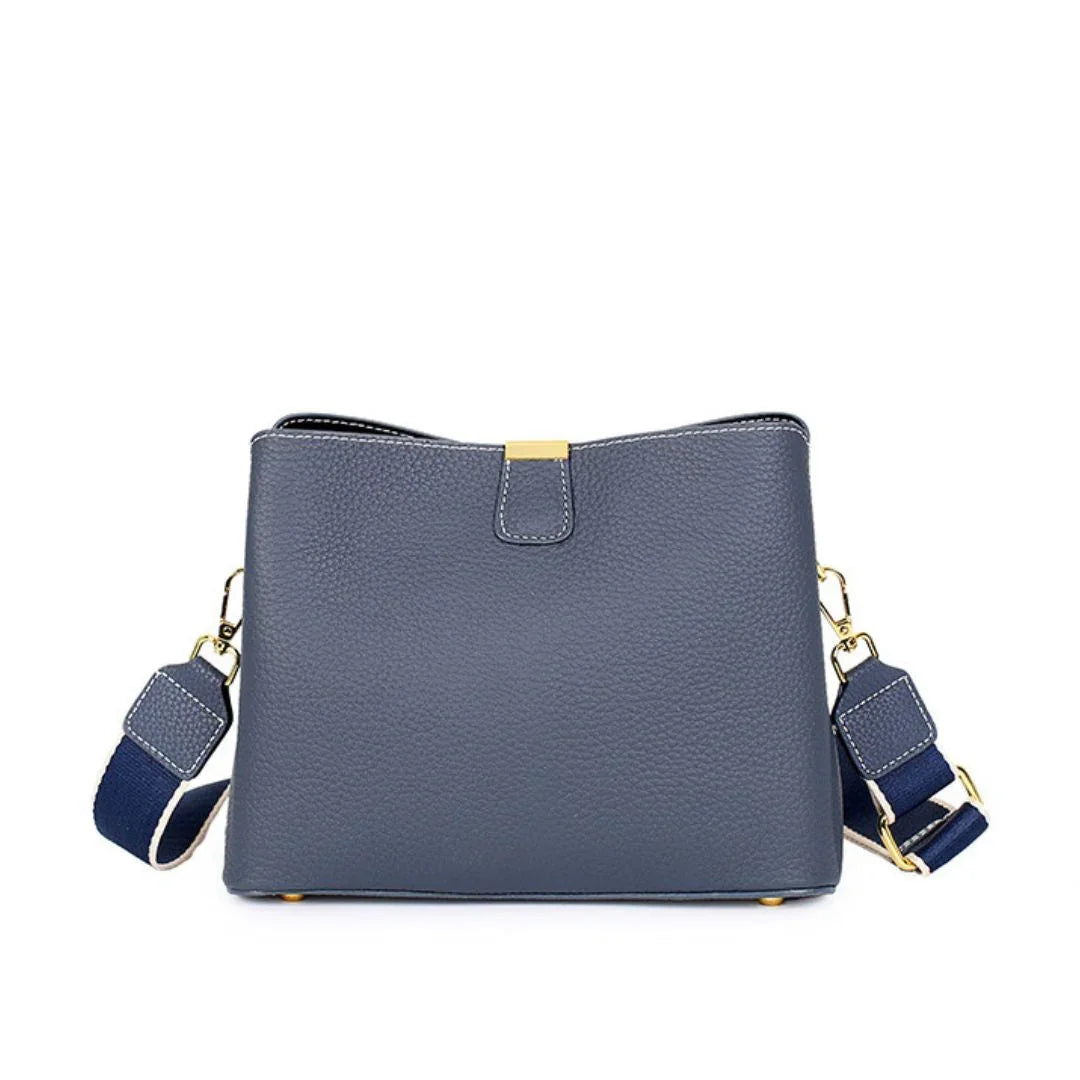 Navy blue leather crossbody bag with gold hardware and adjustable strap on white background