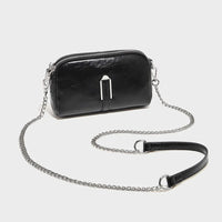 Black leather crossbody bag with silver chain strap on white background