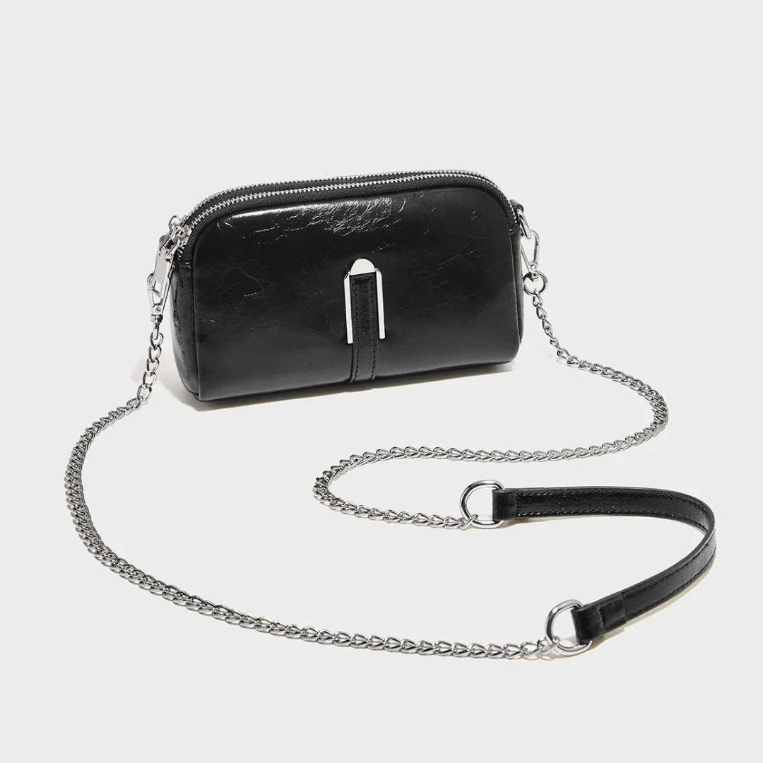 Black leather crossbody bag with silver chain strap on white background