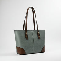Green and brown leather tote bag with long handles on plain background