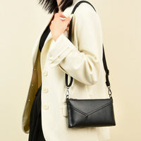 Woman wearing cream blazer with black leather crossbody purse, minimalist fashion style