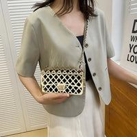 Woman wearing beige short-sleeve blazer with gold lattice crossbody bag