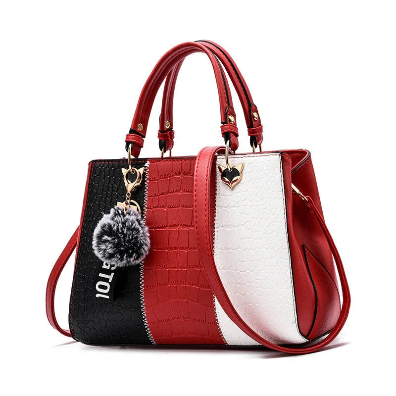 Red, black, and white crocodile pattern handbag with gold heart hardware and fur pom pom keychain