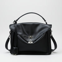 Black leather handbag with top handle and silver clasp on white background