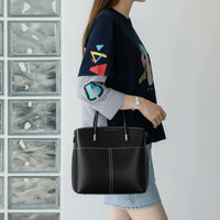 Woman wearing a graphic navy shirt and holding a black leather handbag