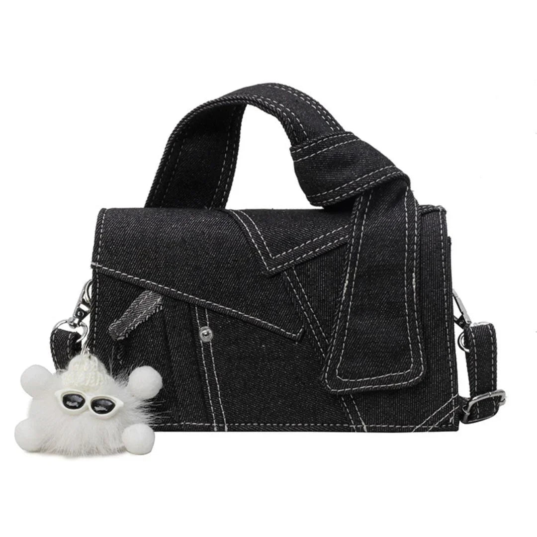 Black denim handbag with white stitching and a fluffy white sunglasses keychain