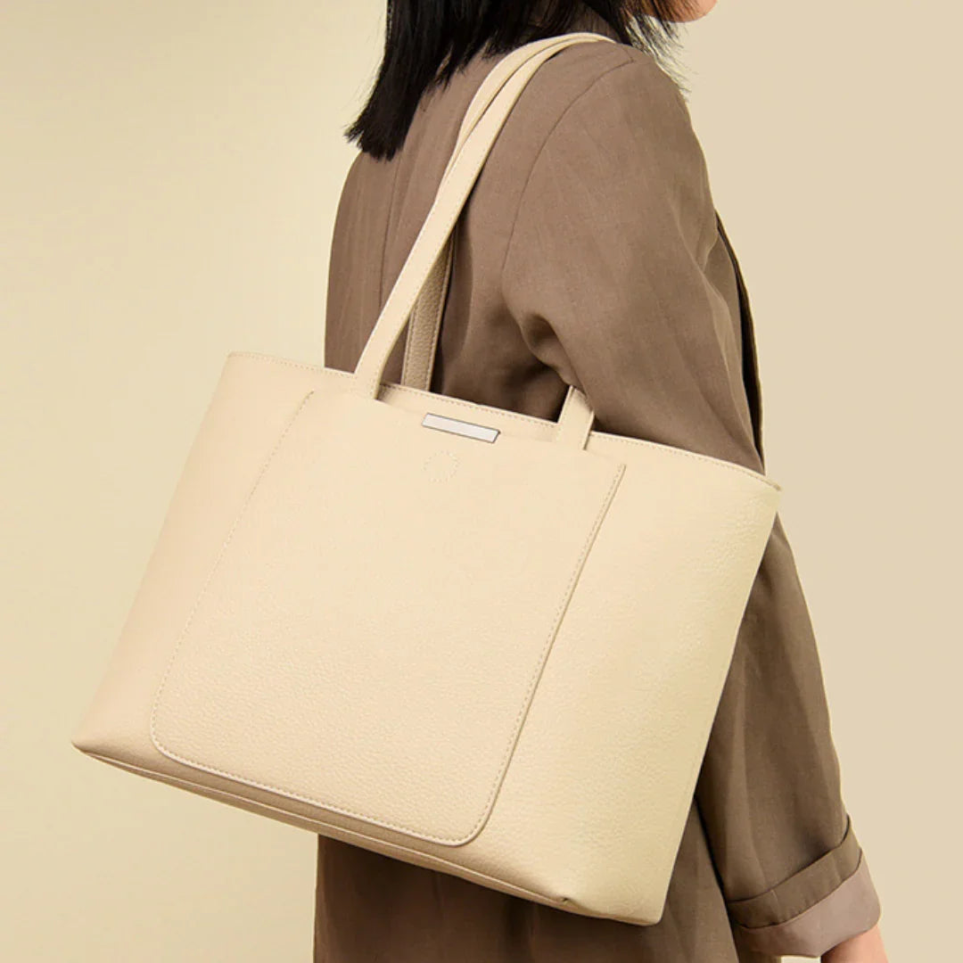 Woman in brown blazer carrying large beige leather tote bag on shoulder