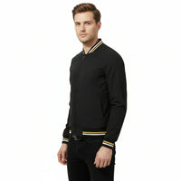 Man wearing a black bomber jacket with yellow accents on a white background