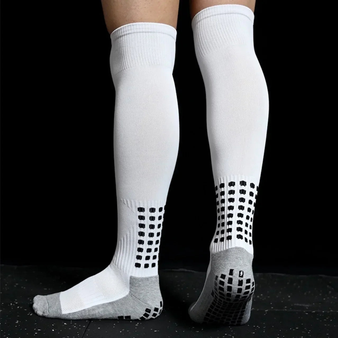 White knee-high socks with gray soles on a black background
