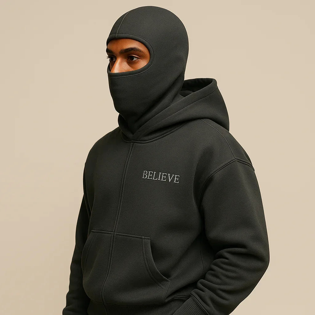 Person wearing a black hoodie with 'BELIEVE' text on a beige background