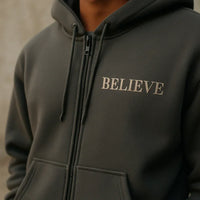 Dark gray hoodie with 'BELIEVE' text on a neutral background