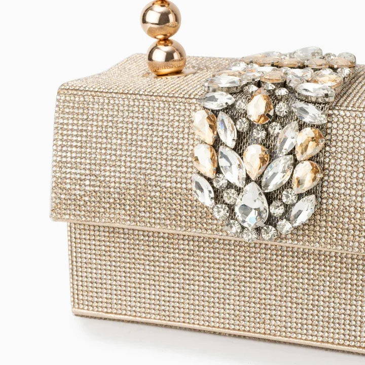 Embellished gold clutch purse with crystal gems and gold ball clasp on white background