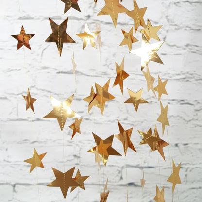 Gold star-shaped decorations hanging against a white brick wall.