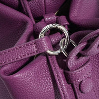 Close-up of purple leather handbag with silver ring detail