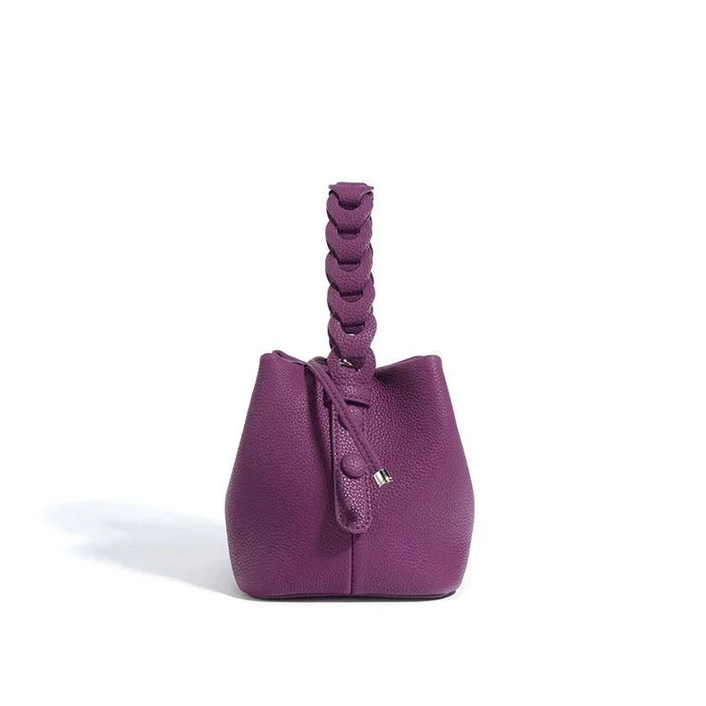 Purple leather bucket bag with braided handle on white background