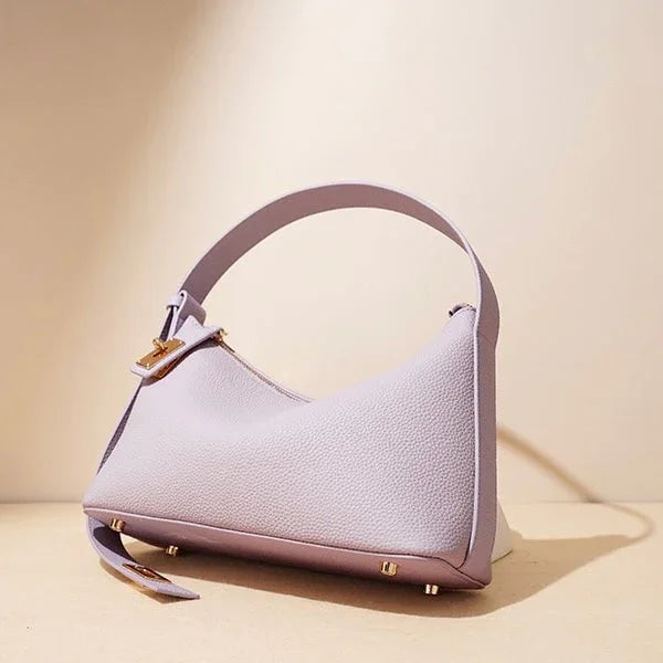 Lavender textured leather shoulder bag with gold hardware on beige background