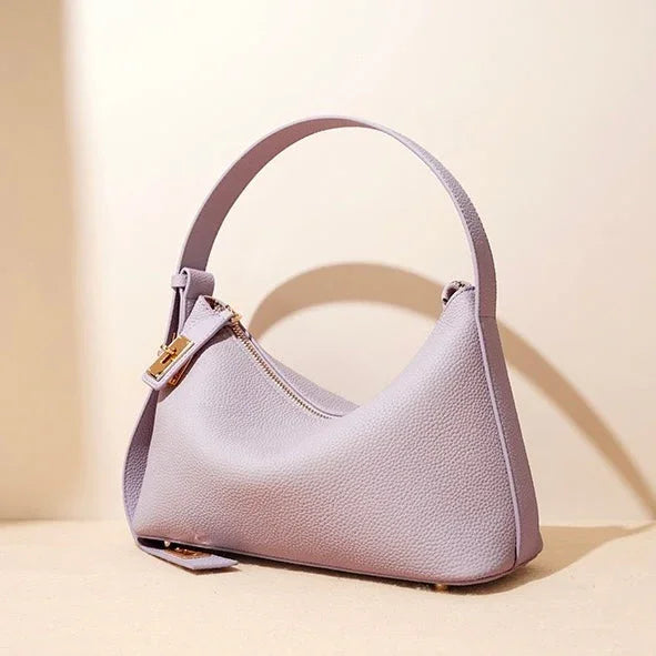 Lavender leather shoulder bag with gold zipper on beige background