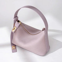 Light purple leather handbag with gold zipper and buckle on a white background