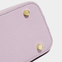 Bottom of lavender textured leather handbag with gold metal feet on white background