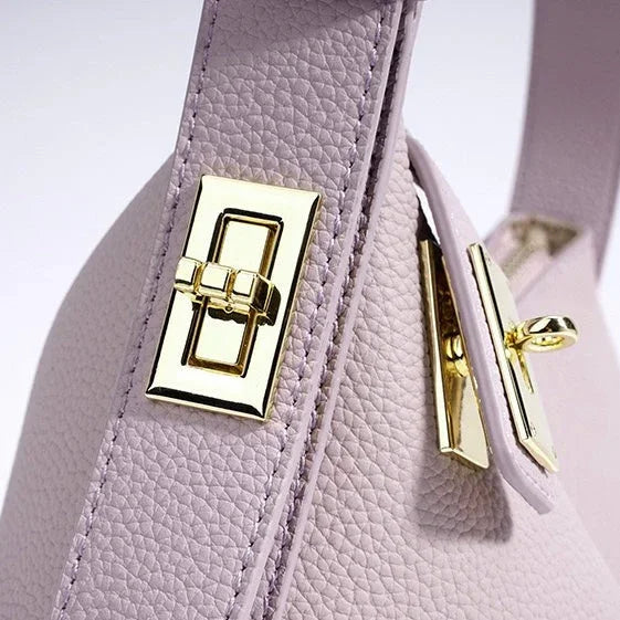 Close-up of lavender leather handbag with textured surface and gold-tone metal clasp