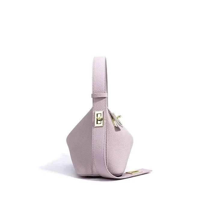 Light pink leather handbag with gold hardware, modern geometric design, white background