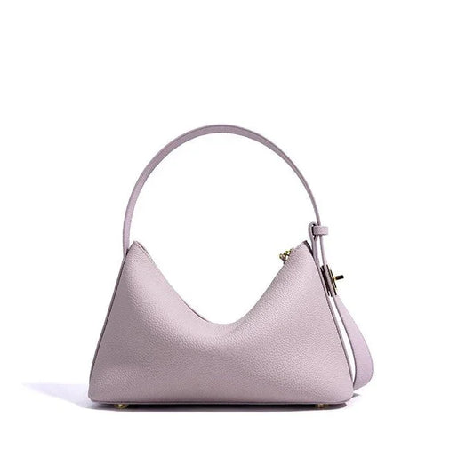 Pastel purple leather handbag with top handle and gold hardware on white background