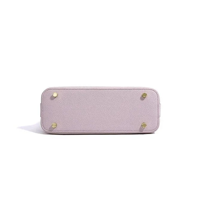 Light purple leather handbag bottom with gold metal feet on white background