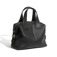 Black leather handbag with gold zipper and dual handles on white background