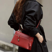 Woman in black coat carrying a stylish red leather handbag with gold hardware