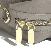 Close-up of a gray leather handbag with gold zipper and double gold zipper pulls