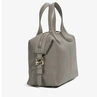 Taupe leather handbag with double handles, gold zipper, and textured finish on white background