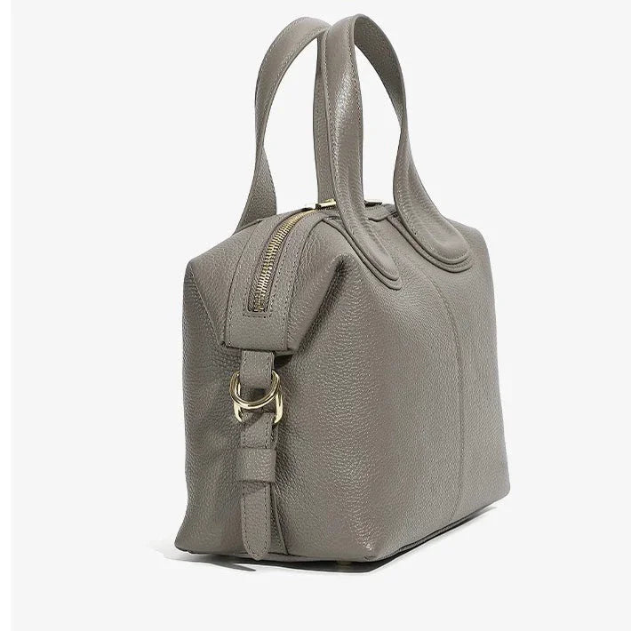 Taupe leather handbag with double handles, gold zipper, and textured finish on white background