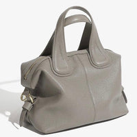 Taupe leather handbag with double handles, gold hardware, and zipper closure on white background