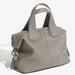 Taupe leather handbag with double handles, gold hardware, and zipper closure on white background