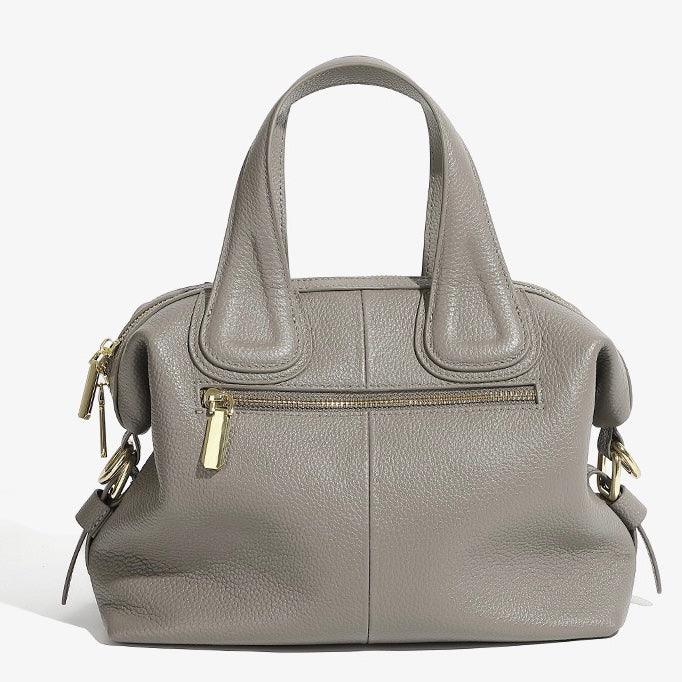 Taupe leather handbag with gold zippers and top handles on white background