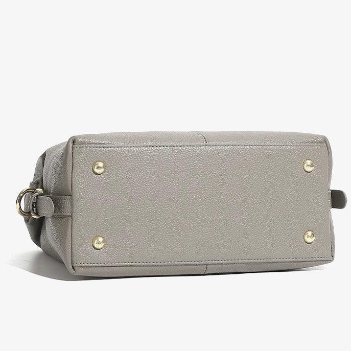 Bottom view of gray leather handbag with gold metal feet on white background