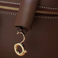 Brown leather bag with gold clasp, visible zipper and detailed stitching