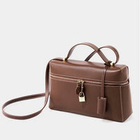 Brown leather crossbody bag with top handle, gold zipper, and lock accents on white background