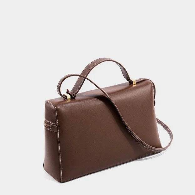 Brown leather handbag with top handle and shoulder strap on white background