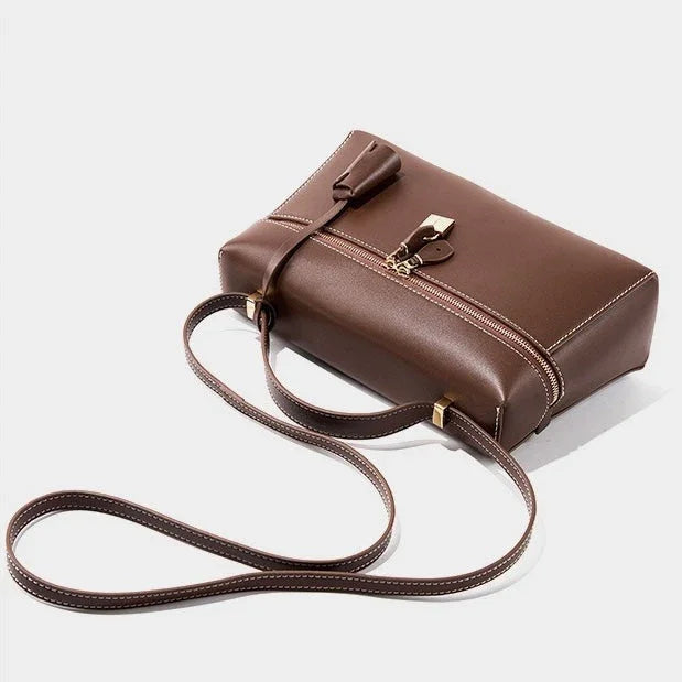 Brown leather crossbody bag with gold zipper and lock on white background