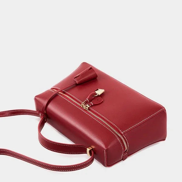 Red leather handbag with gold zipper and hardware on a white background