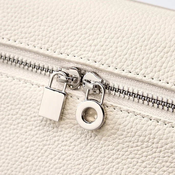 Close-up of white textured leather bag with silver zipper and padlock detail