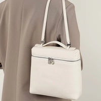 Cream leather crossbody bag with silver zipper on beige blazer