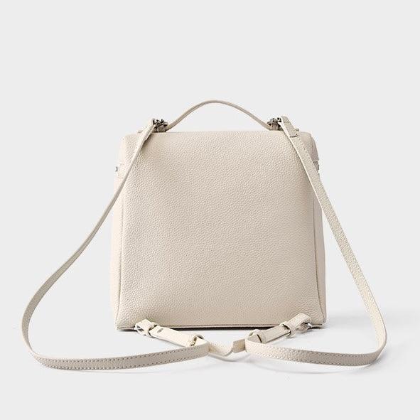 Beige leather backpack purse with adjustable straps on a white background