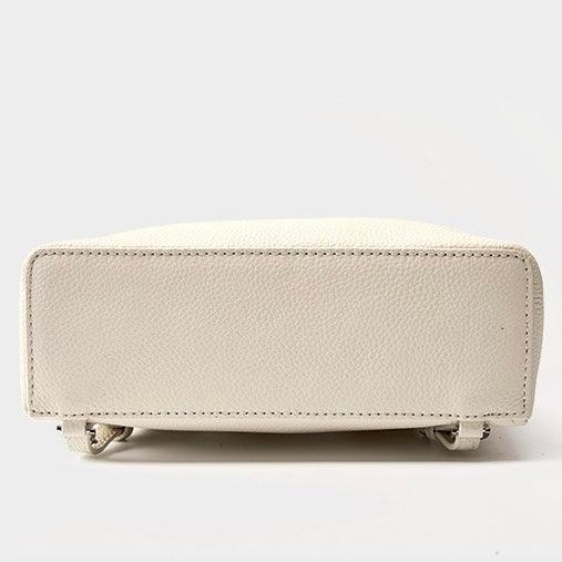 Bottom view of a textured cream leather handbag on a plain light background