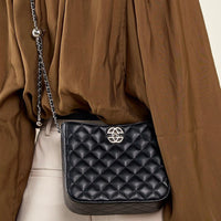 Black quilted leather crossbody bag with silver chain strap and brown blouse