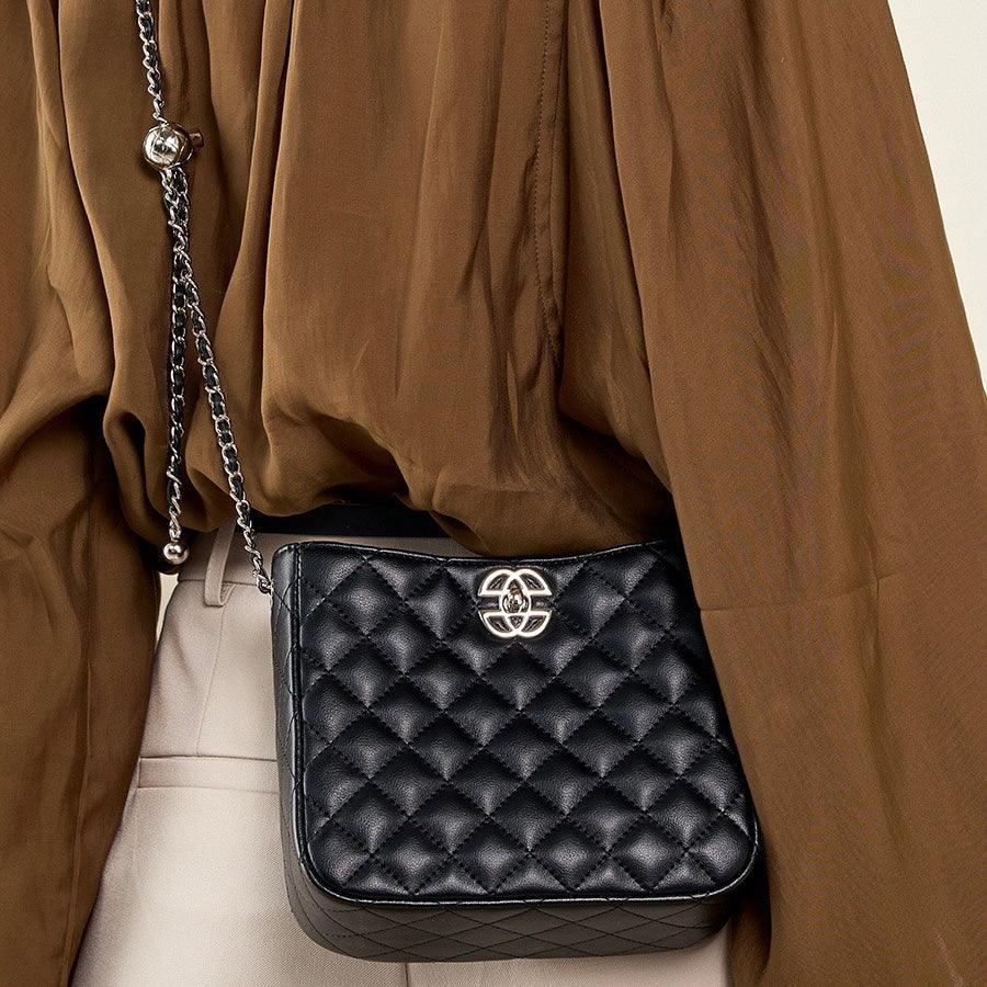 Black quilted leather crossbody bag with silver chain strap and brown blouse